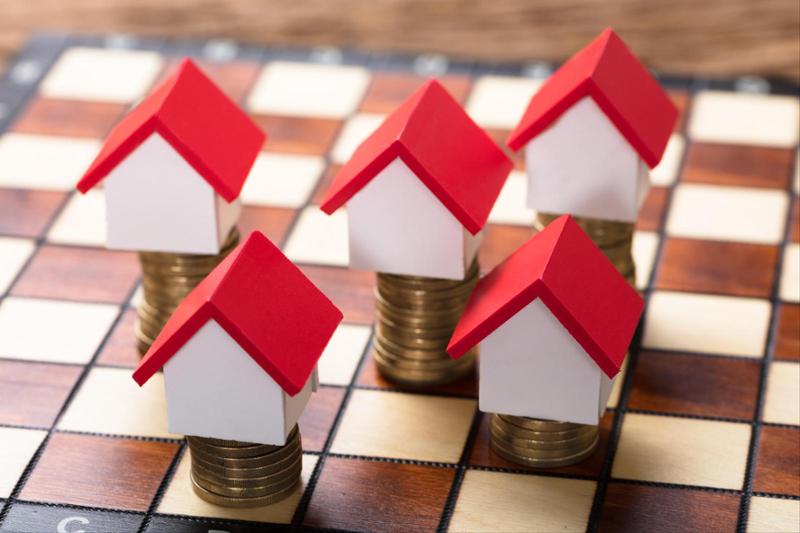 checkerboard with small houses on the squares sitting atop a short stack of pennies